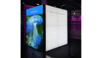 Kubischer Messestand mit leuchtender LED-Wand und farbiger Grafik einer Qualle, sichtbar Website-URL.