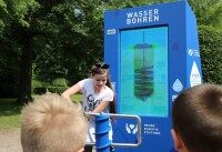 Multimedia-Station Wasserbohren bei der Wasser-Rallye. Kinder bedienen blaue Station zum Wasserbohren bei interaktiver Ausstellung im Park.