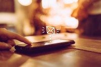 Finger berührt Smartphone-Bildschirm, animiertes Symbol einer Nachrichteneingangsbuchse als Hinweis auf Push-Benachrichtigungsfunktion.