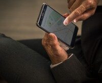 Wrocklage App zur Einsatzplanung, mit Echtzeitübersicht für die Disposition und automatischer Wettererfassung für den Garten- und Landschaftsbau. Person in Anzug nutzt Smartphone-App zur Standortbestimmung mit Karte, Einsatz im Garten- und Landschaftsbau zur digitalen Einsatzplanung.