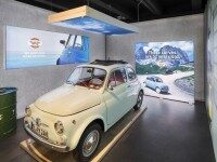 Ausstellungsraum mit weißem Oldtimer, Decken-Leuchtbild und LED-Leuchtwand mit Bergmotiv