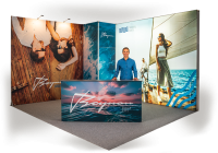 Messestand mit großflächiger Rückwand und bedruckter Theke, dekoriert mit maritimen Motiven und einer Person am Stand