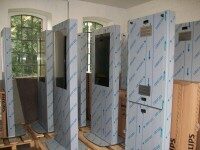 Mehrere unbenutzte Werbestelen in einem Raum mit schützender Folie umwickelt.