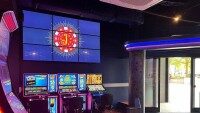 Computerspielautomaten mit bunten Bildschirmen und einem großen beleuchteten Logo mit einem J im Hintergrund.