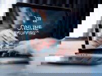 Laptop mit geöffneter Online-Shopping-Website, Hand zeigt auf den Bildschirm.