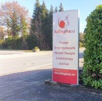 Aluminium-Werbestele mit reflektierender Folie für hohe Sichtbarkeit im Außenbereich Außenaufnahme eines Aluminium-Pylons mit rotem Text auf reflektierender weißer Folie. Die Werbestele steht am Straßenrand und bewirbt ein Therapiezentrum.