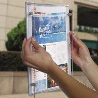 Person wechselt ein Exposé in einem transparenten LED-Schaufensterrahmen, Beispiel für einfach zu bedienende Präsentationssysteme