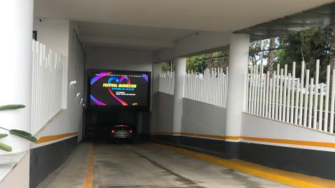 Videowand im Parkplatz Ein Auto fährt durch einen Tunnel mit einem digitalen Plakat Videowand über einem Festival.