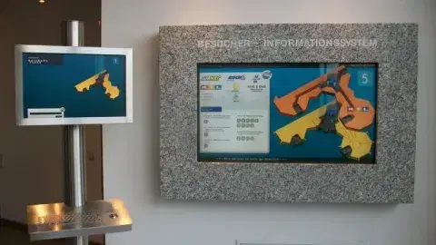 Monitor in einem speziellen Wandgehäuse mit grauer Granitverkleidung und entspiegeltem Glas