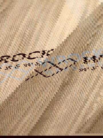 Graviertes Wrocklage-Logo auf heller Holzoberfläche als Beispiel für Materialveredelung und Branding